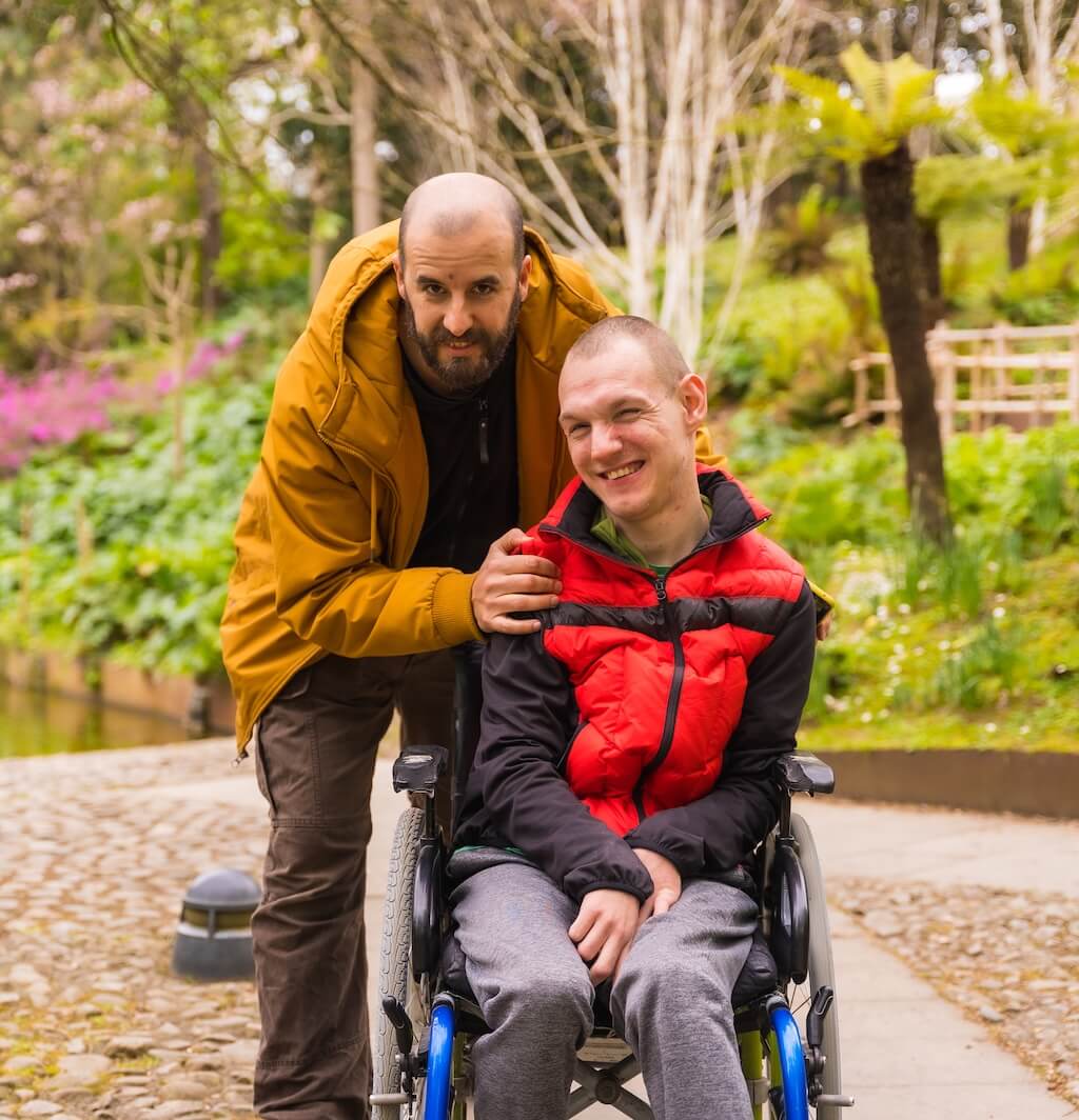 Man helping another man in a wheelchair at the park