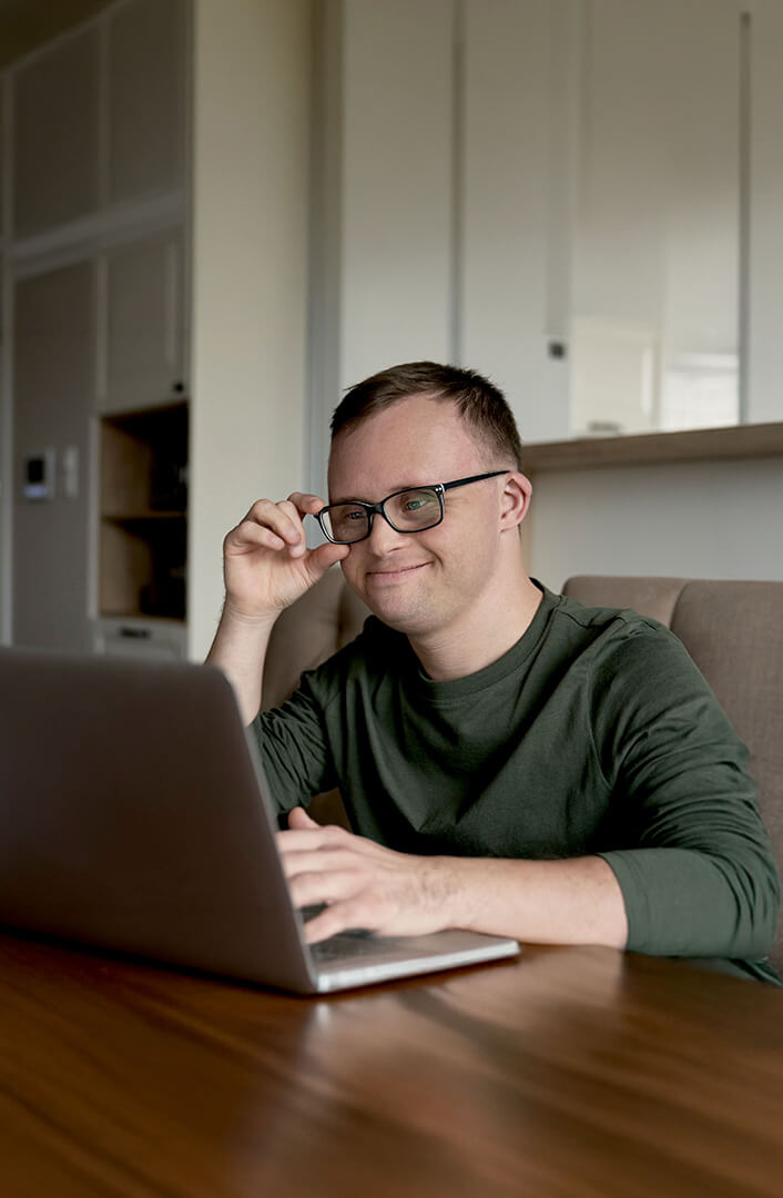 cheerful-adult-man-with-down-syndrome-using-laptop-home(1-scaled)-tinified